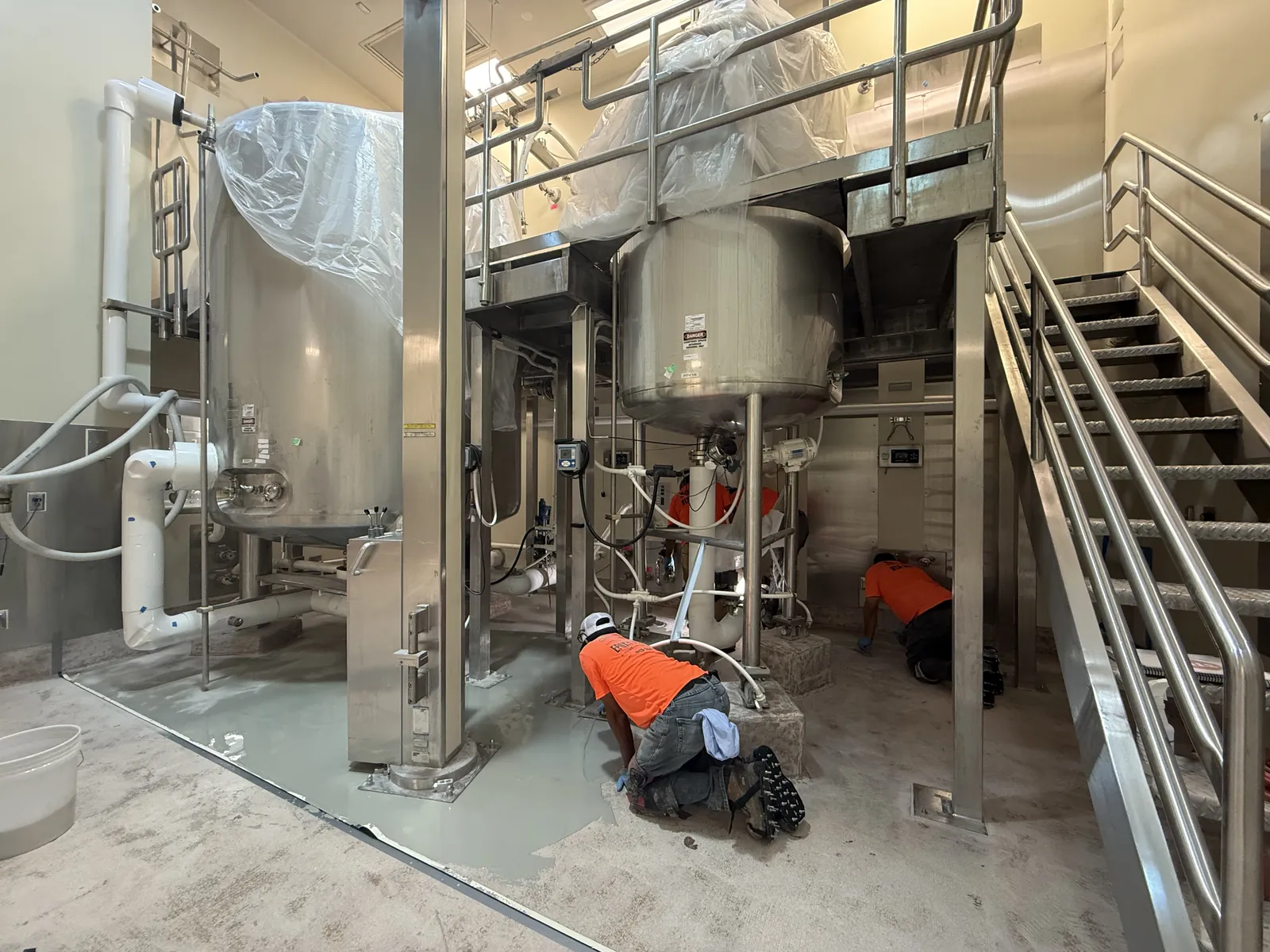 Installer hand-troweling urethane cement beneath processing equipment