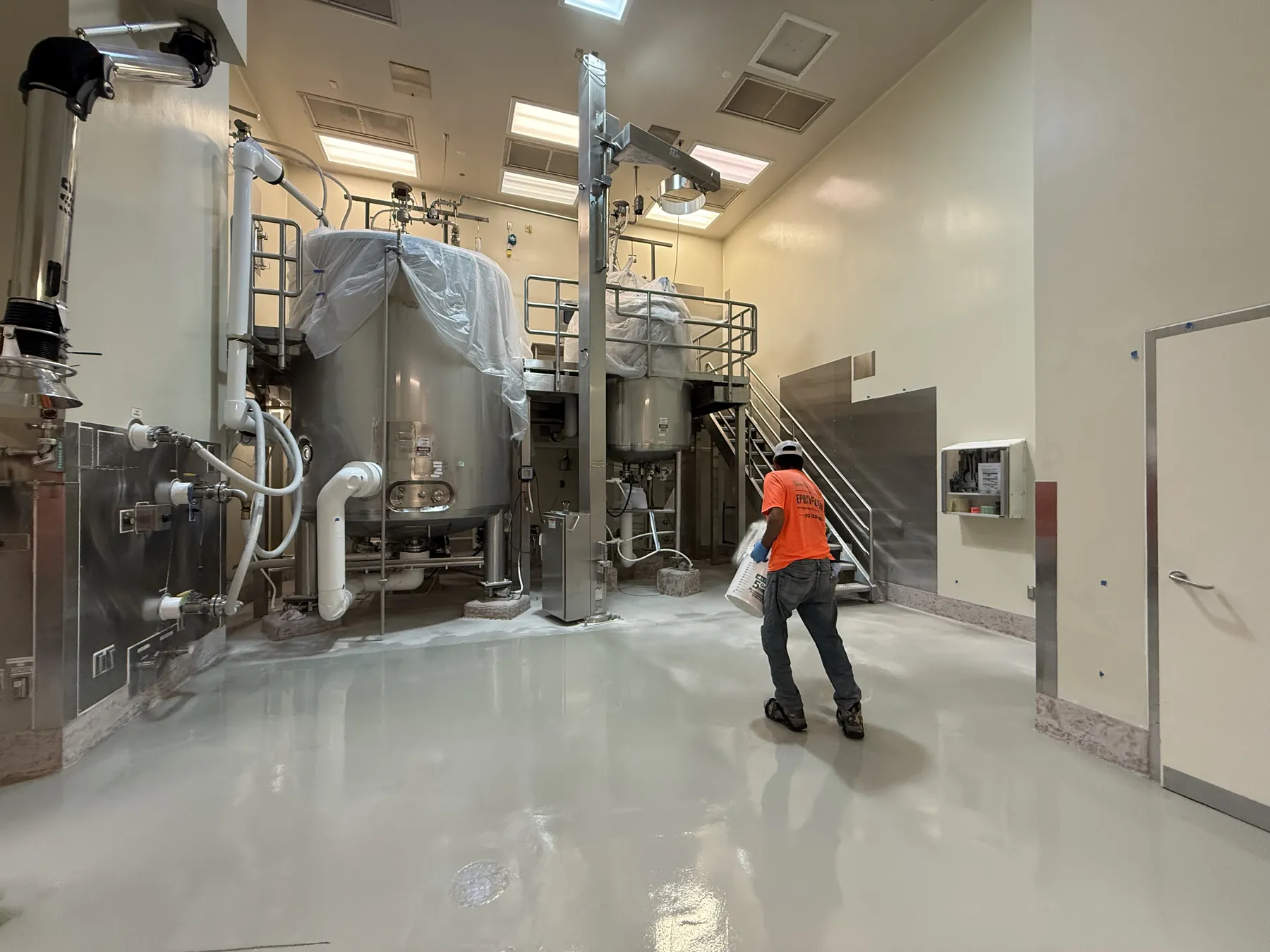 Coated light gray floor beneath stainless steel processing tanks with a GroCo installer