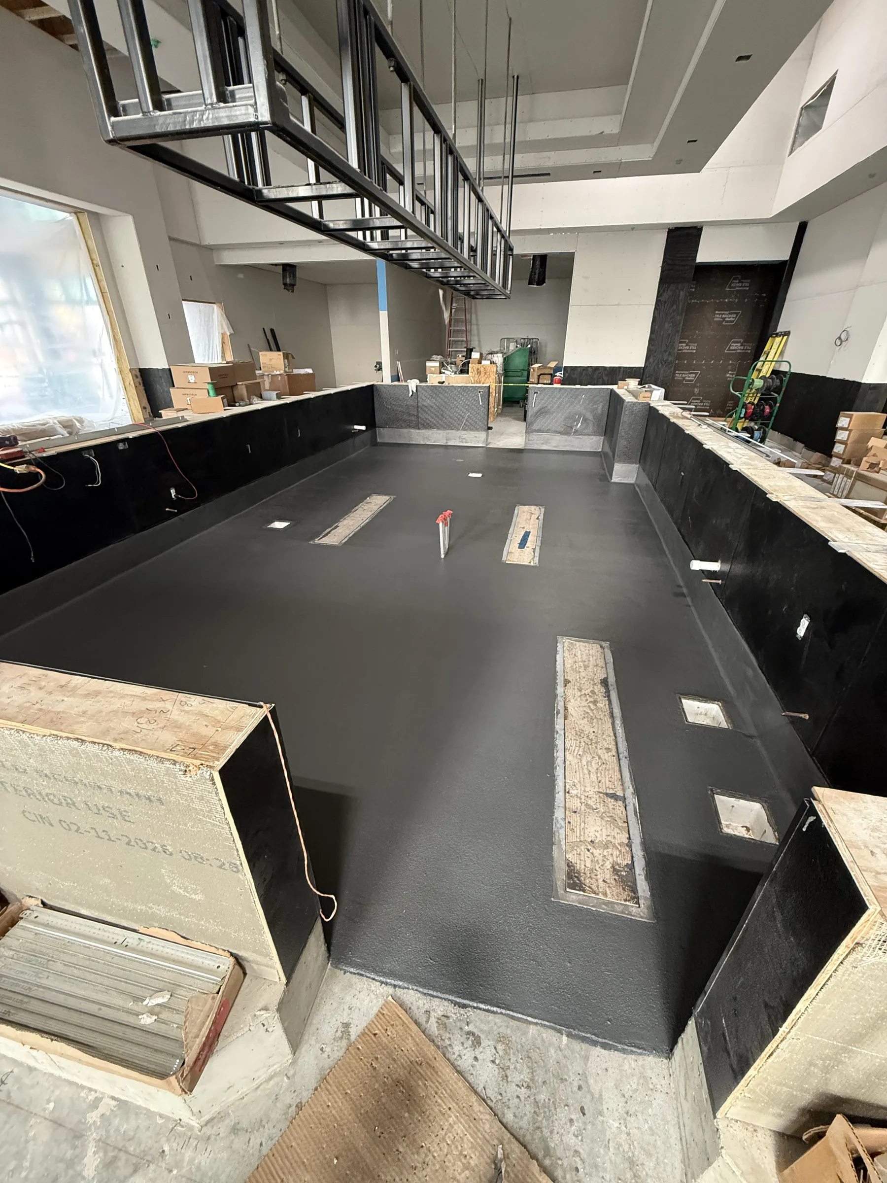 Fresh urethane cement being placed around trench drains in a commercial kitchen