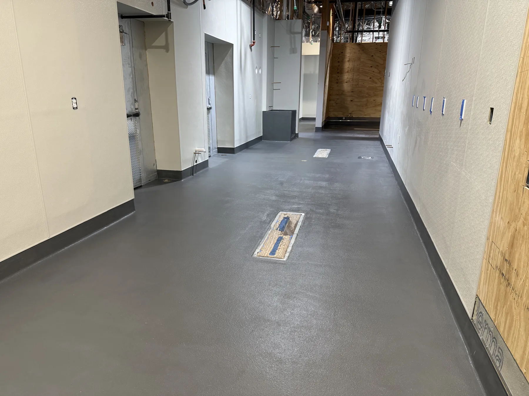 Finished gray urethane cement floor with integral cove base in a commercial kitchen corridor