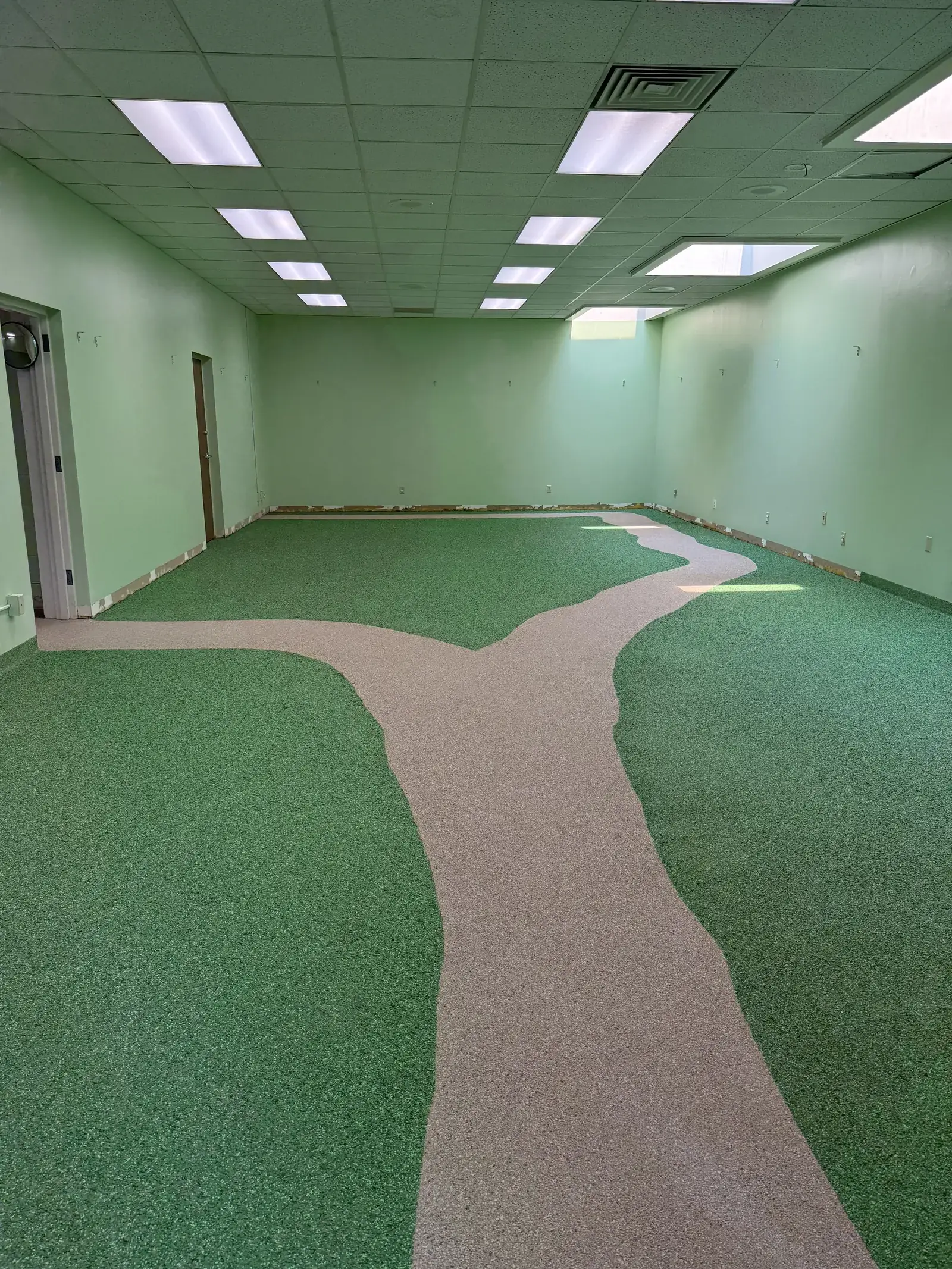 Green decorative flake epoxy floor with a winding tan path in an empty school library