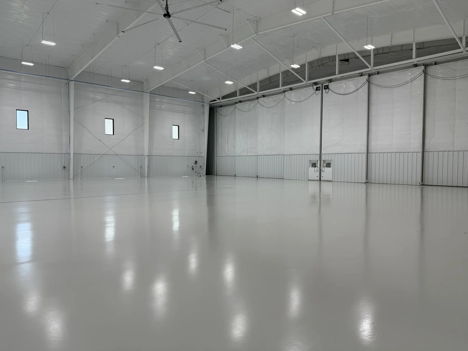 Aircraft hangar epoxy floor reflecting overhead lights with hangar door closed