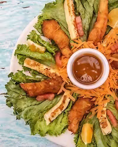 Plate with fried seafood, lettuce leaves, shredded carrot, and a cup of brown dipping sauce.