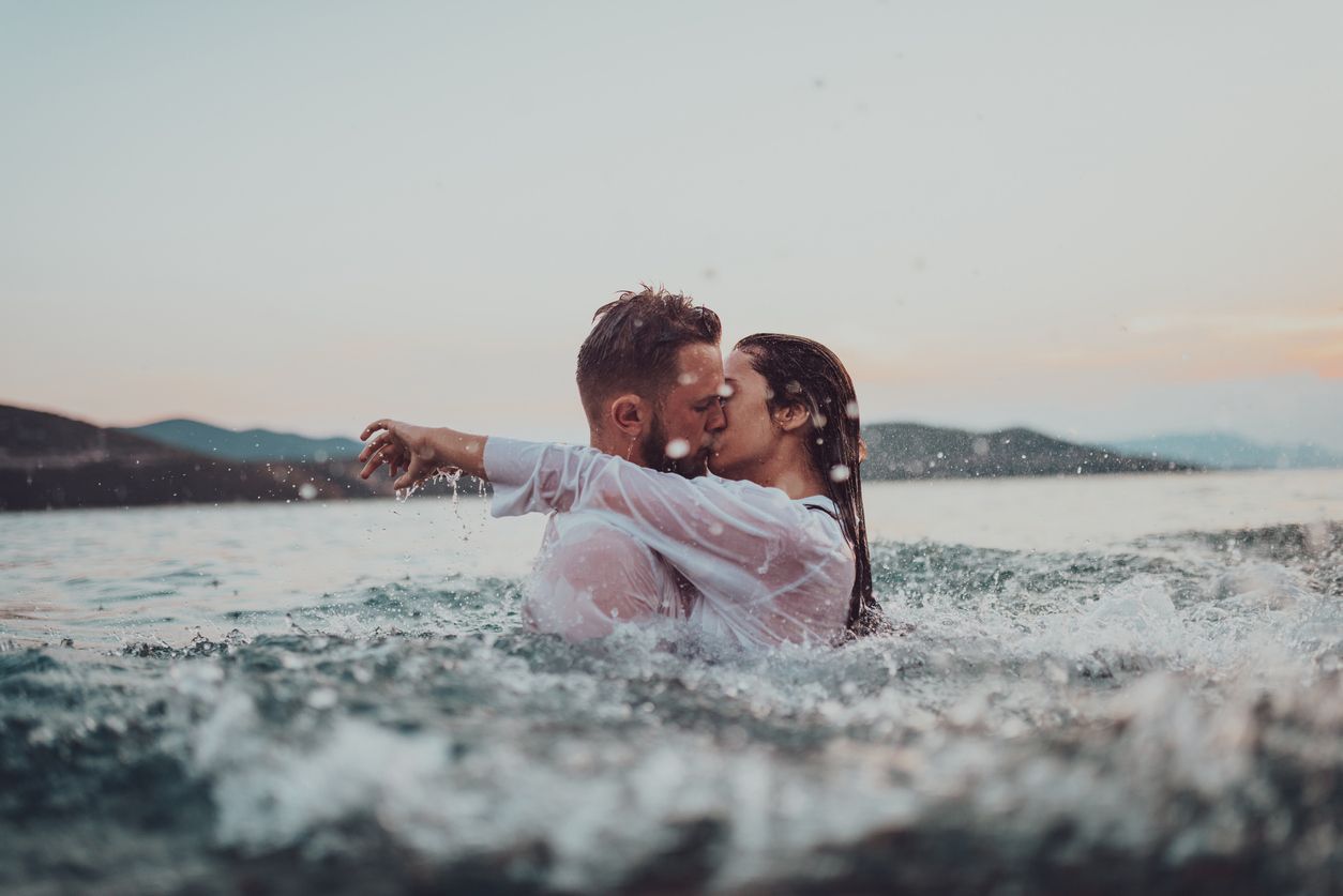 Couple embracing and kissing in the surf