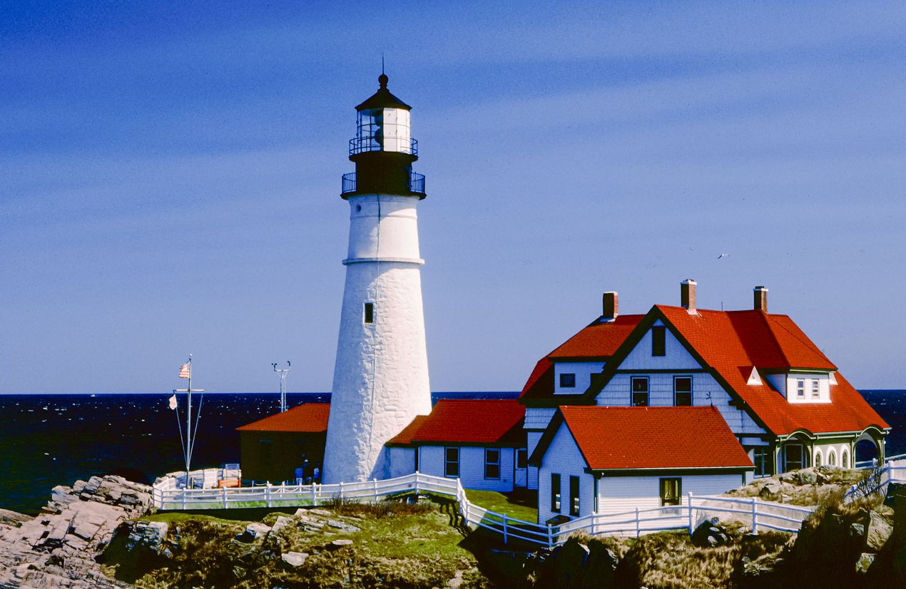 White lighthouse and red-roofed keeper's house on a rocky shore