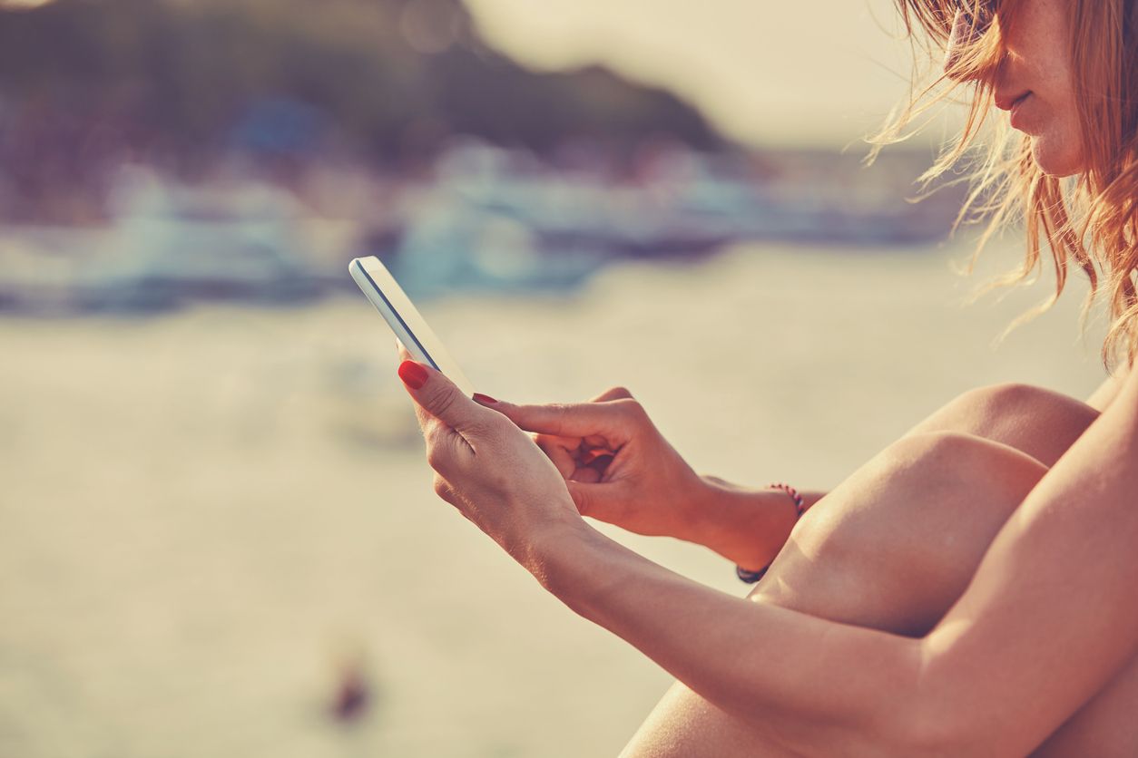 Woman sitting outdoors in the sun, looking at her phone