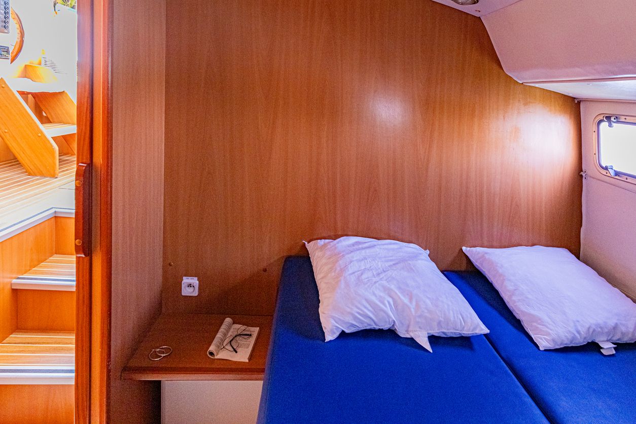 Small cabin berth on a boat with blue cushions and white pillows