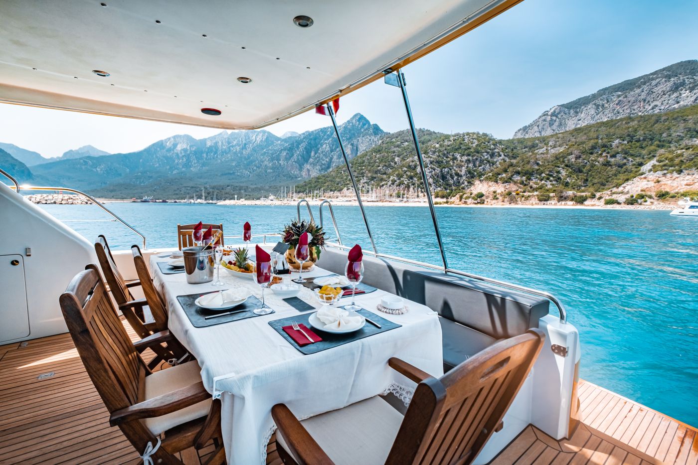 Dinner table set on the deck of a yacht above turquoise water