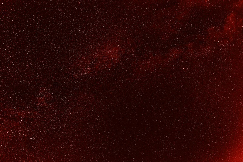 Dark red night sky filled with numerous small white stars scattered across.