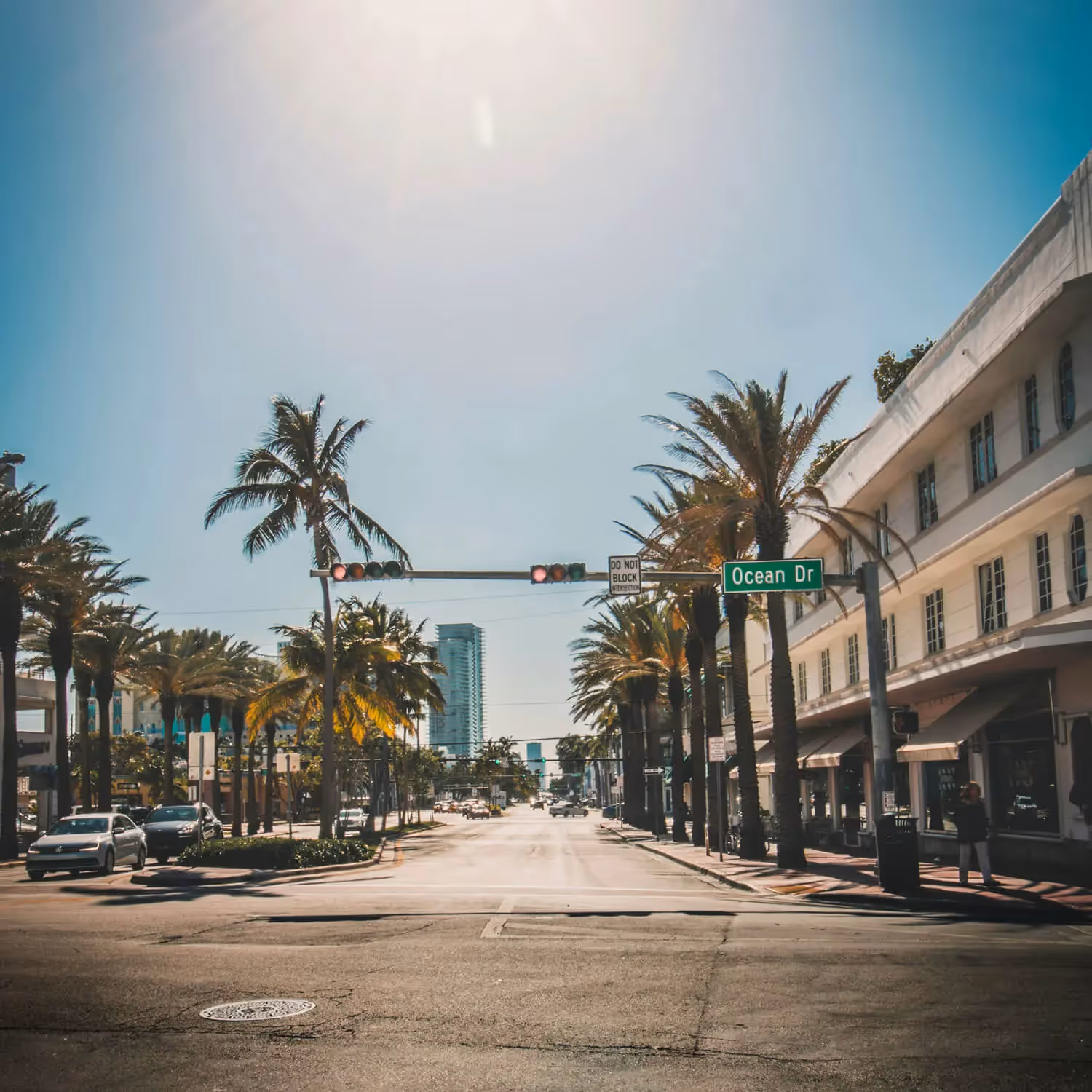 Ocean Drive street with palm trees, historic buildings, and clear blue sky in Miami Beach