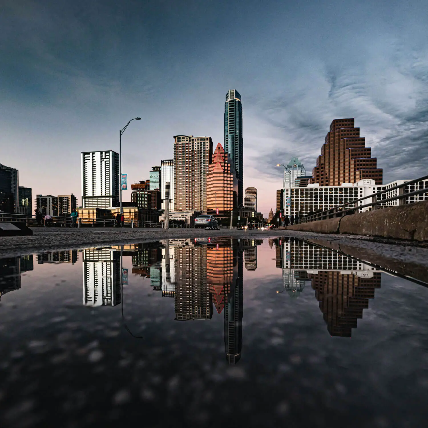 Austin skyline reflected in calm water with modern buildings and blue sky.