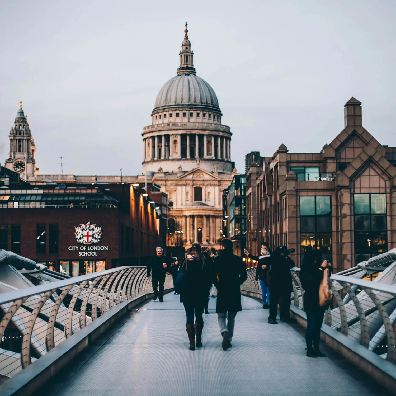 Pedestrians walking across Millennium Bridge toward St. Paul's Cathedral in London.