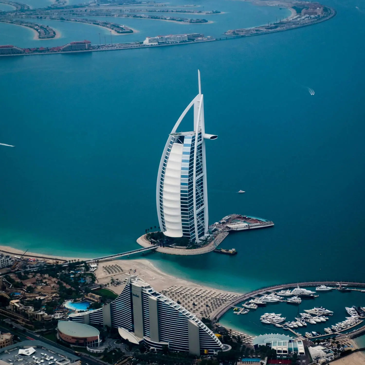 Aerial view of Burj Al Arab luxury hotel in Dubai surrounded by turquoise water