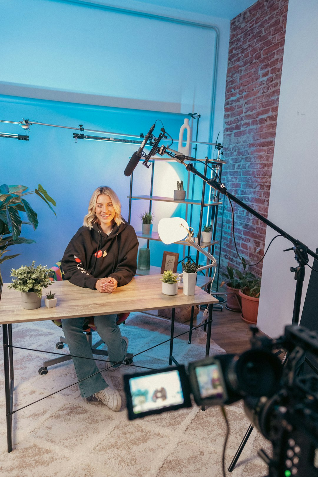 YouTube content creator sitting at a professional recording studio desk with camera equipment and microphone preparing to film a new video