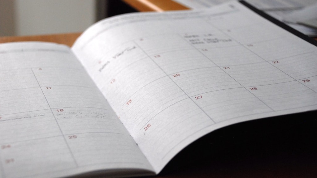 Open planner notebook and calendar on a desk used to set time-bound deadlines for measurable goals