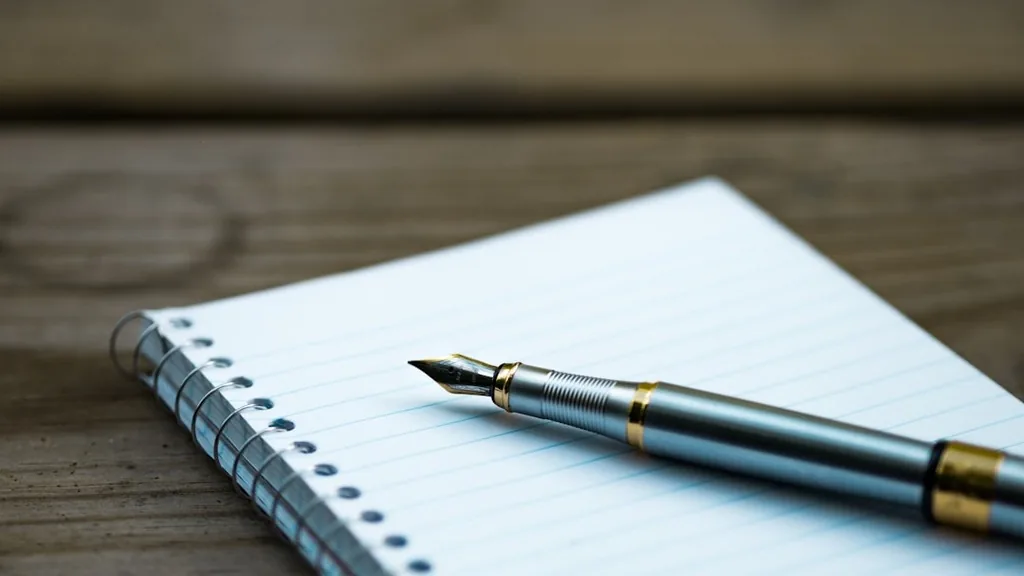 Notebook and pen on a desk used to draft and edit an elevator pitch down to 70 words