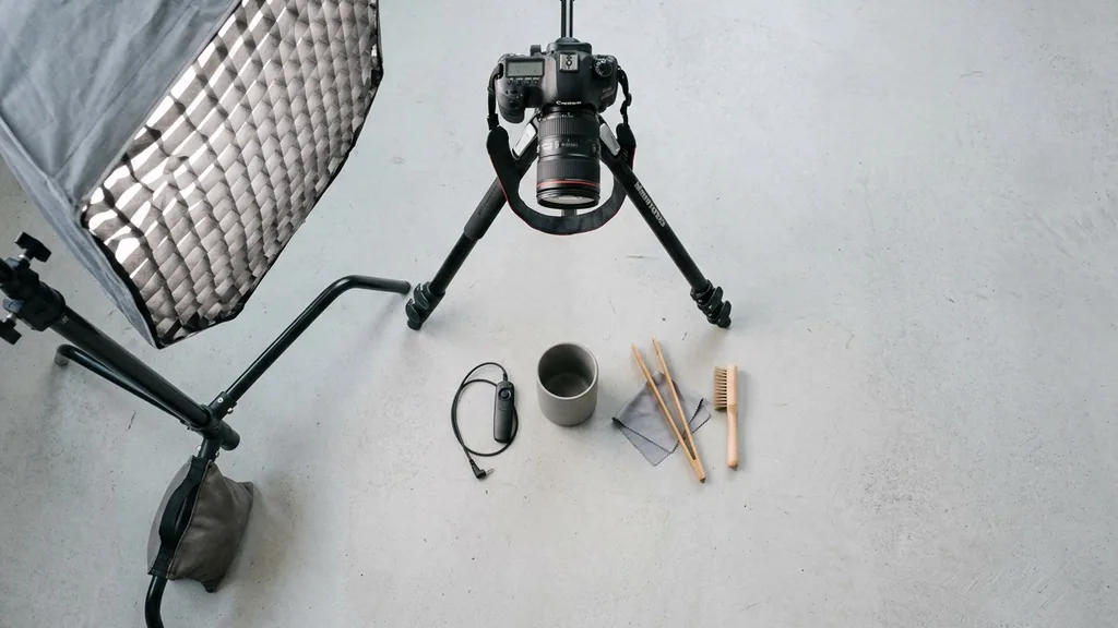 Overhead flat-lay product photography setup with a plain product, softbox light and tripod camera