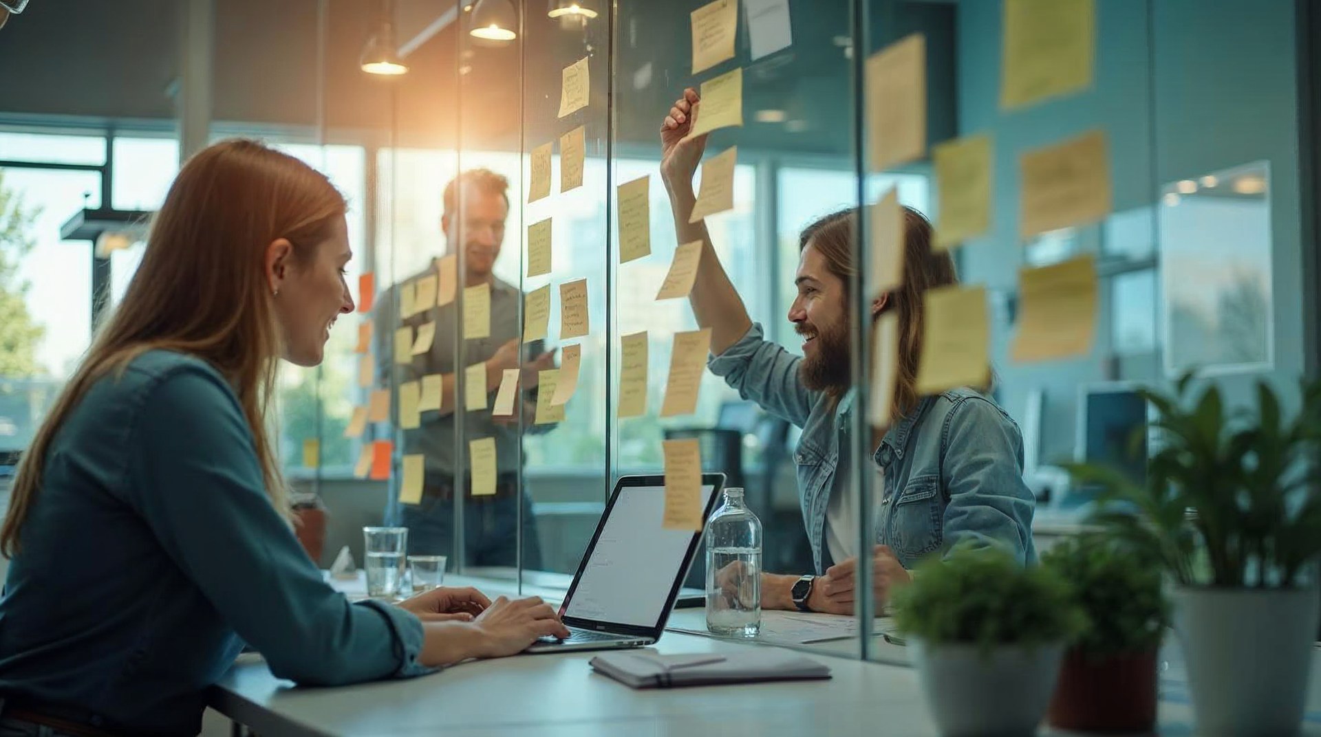 Two colleagues at a desk mapping CRM objects on sticky notes beside a laptop