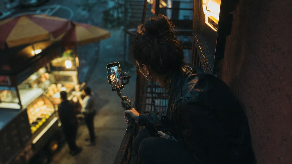 Creator filming a product on a kitchen counter with a phone clamped to a lamp