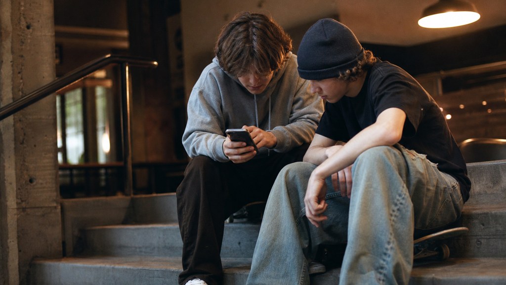 Two teenagers on skateboards looking at a phone on a set of concrete steps, photographed in Spokane