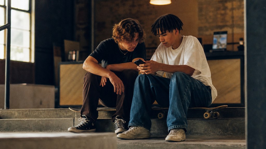 Two teenagers on skateboards looking at a phone on a set of concrete steps, photographed in Tulsa