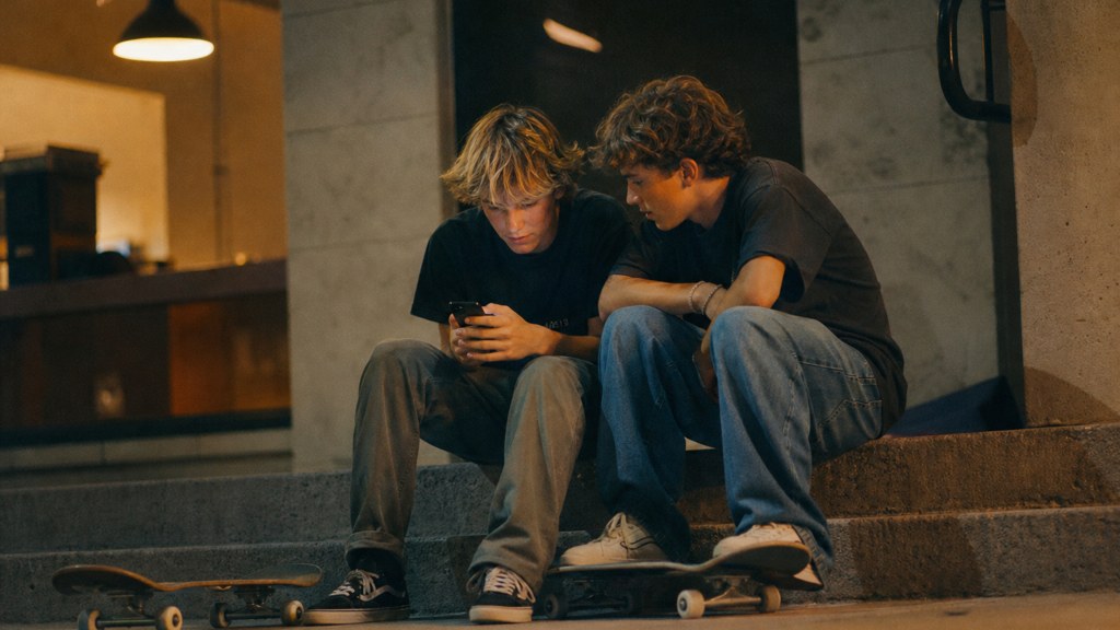 Two teenagers on skateboards looking at a phone on a set of concrete steps, photographed in Virginia Beach