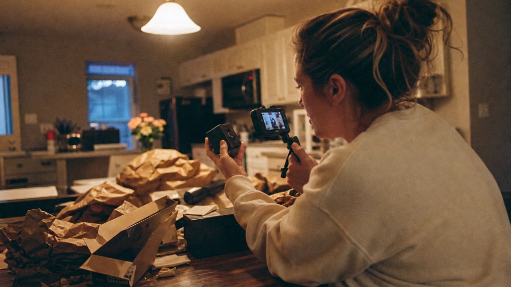 A customer filming an unboxing on a kitchen table strewn with packaging, photographed in Virginia Beach