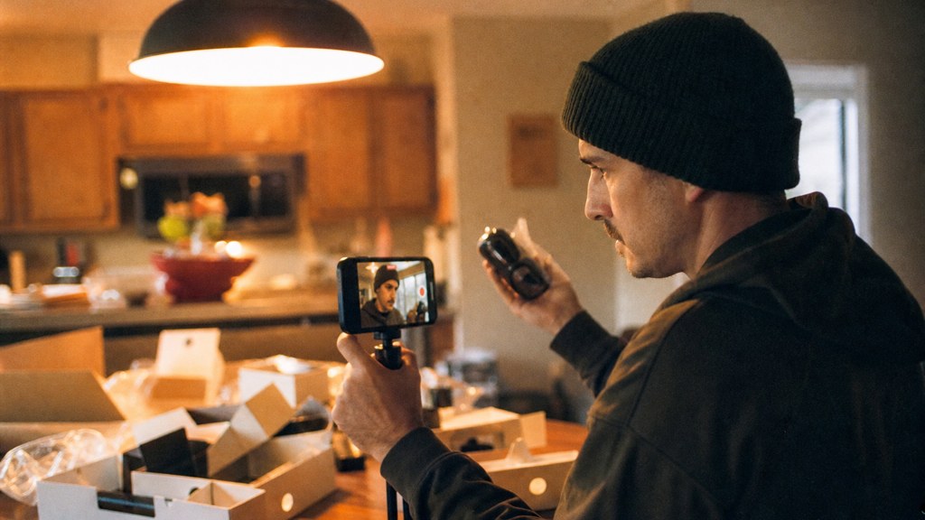 A customer filming an unboxing on a kitchen table strewn with packaging, photographed in Wichita