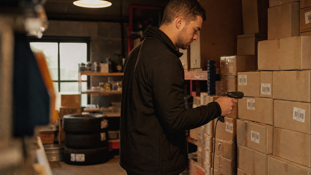 A seller checking barcodes on stacked cartons in a garage stockroom, photographed in Belfast