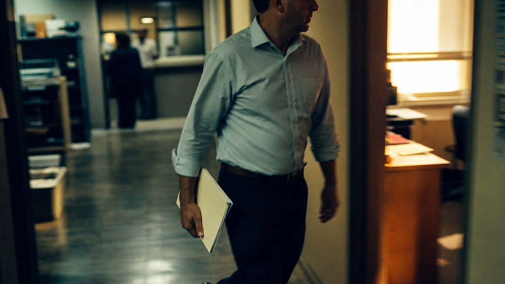 Broker walking through a small lending office holding a folder, captured mid-stride