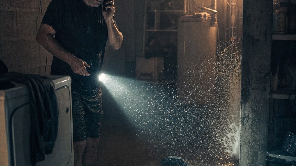 Homeowner standing in a flooded utility room on the phone by torchlight