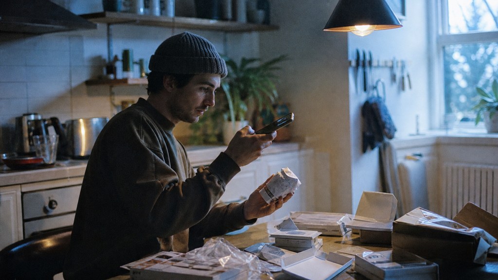 A customer filming an unboxing on a kitchen table strewn with packaging, photographed in Sheffield