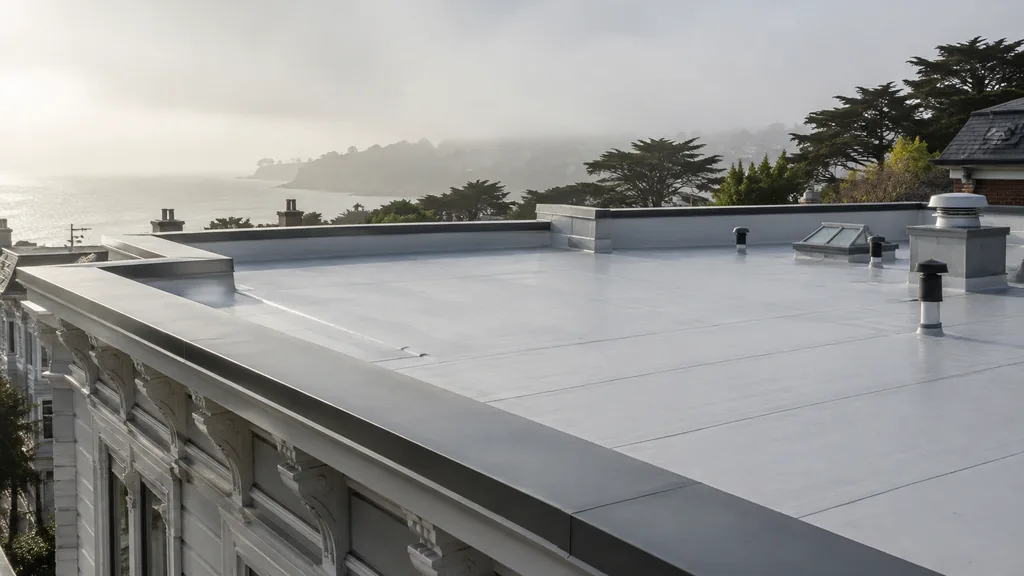 An empty roof surface: a flat white membrane roof on a Victorian-era building with a neat parapet under bright coastal fog light