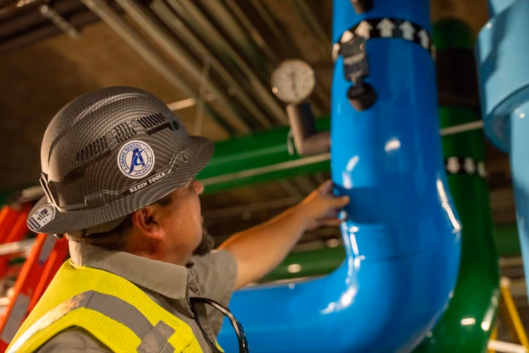 Technician in hard hat servicing chilled water piping