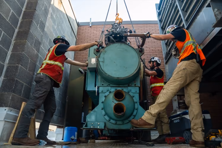 Crew setting a large industrial chiller compressor into place