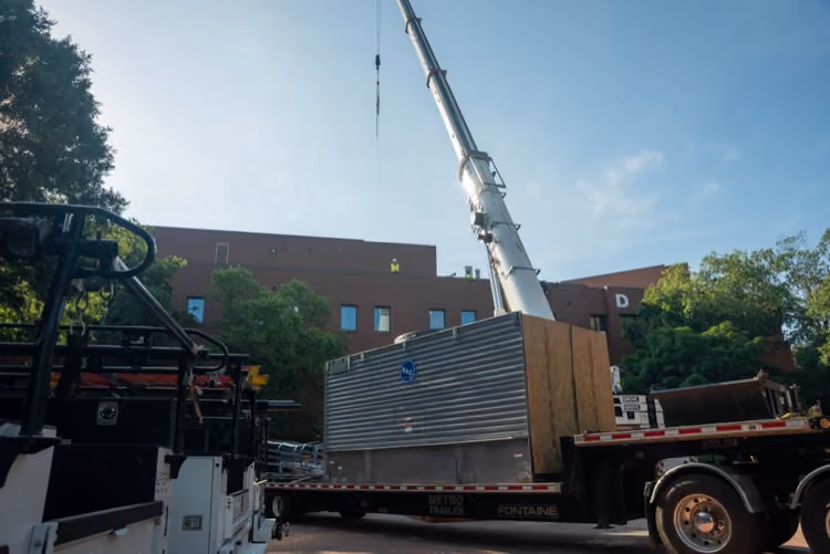 Crane lifting mechanical equipment during a rooftop installation