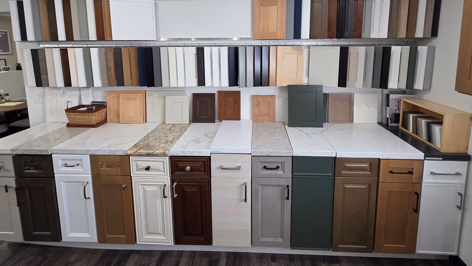 Display of various kitchen cabinet door styles and countertop samples in different colors and finishes.
