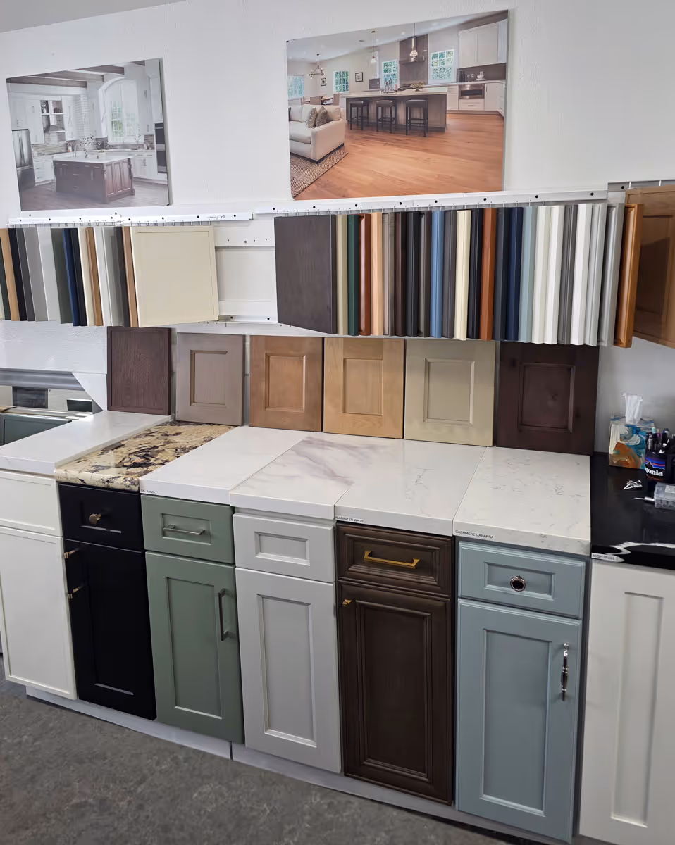 Cabinet door and drawer samples in various colors and finishes displayed on a showroom wall and counter.