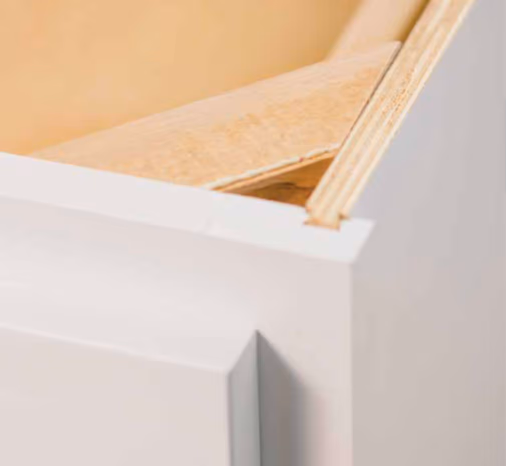 Close-up of a solid wood corner cabinet box with white painted edges.