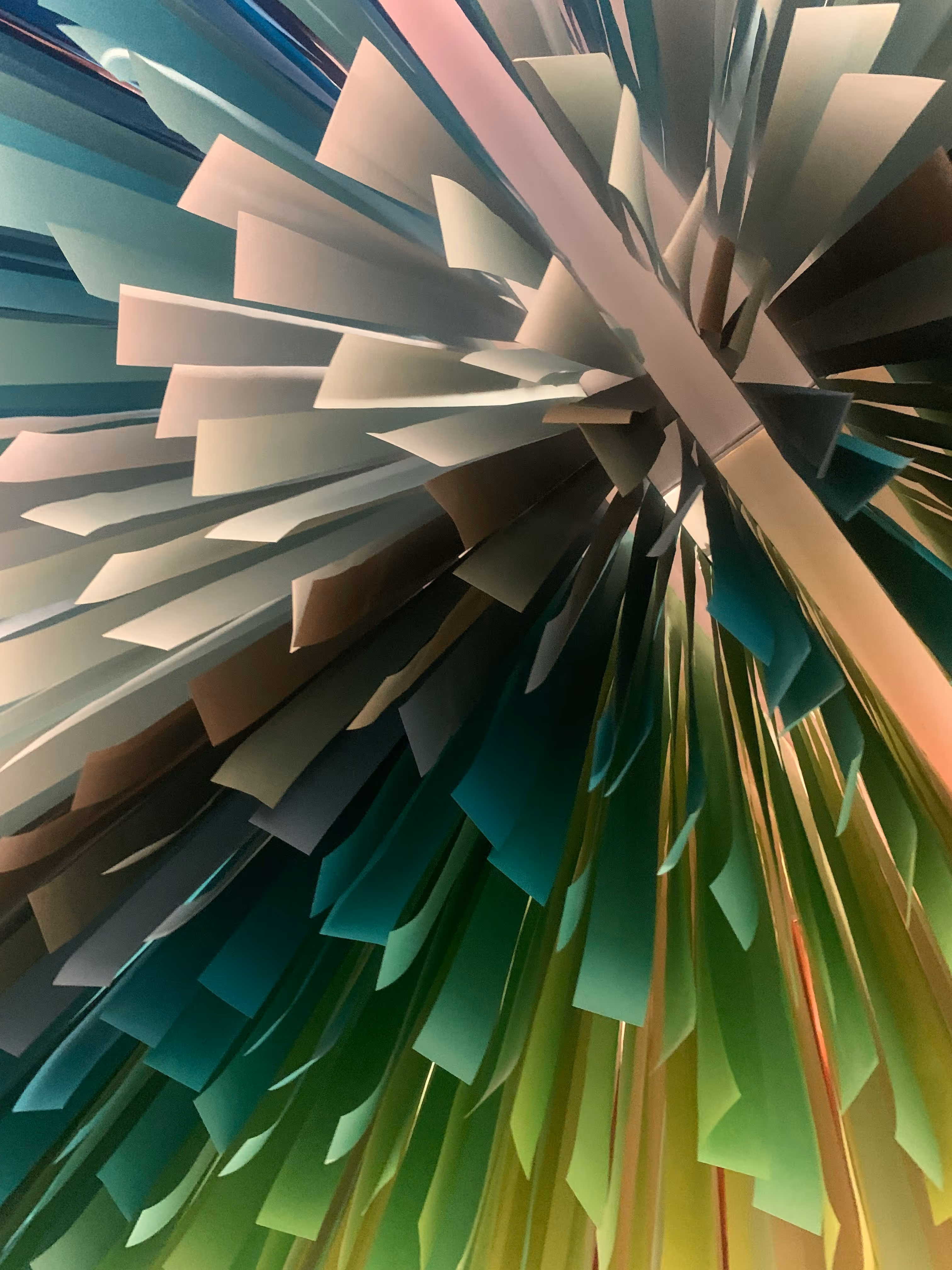 Abstract metallic layered shapes resembling elongated teardrops overlapping on a light blue background.