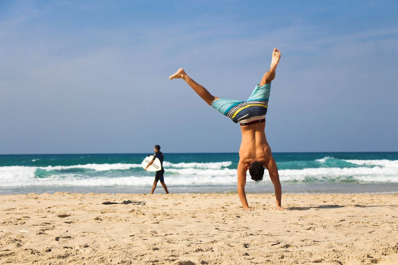man-doing-a-handstand-at-a-beach