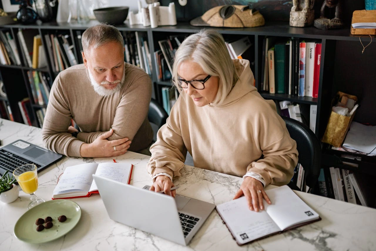 couple-taking-notes-after-looking-at-a-laptop