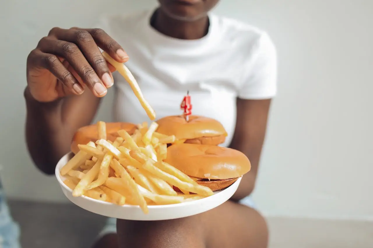 woman eating two burgers and fries