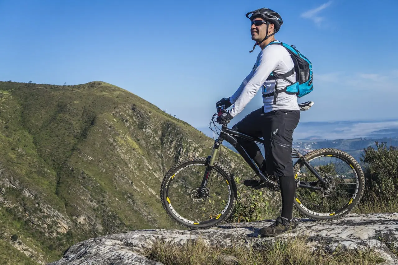 man-holding-a-bike-while-looking-at-mountains