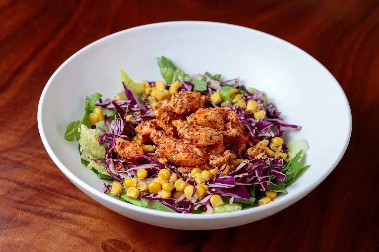 A bowl of chicken, lettuce, corn, and cabbage