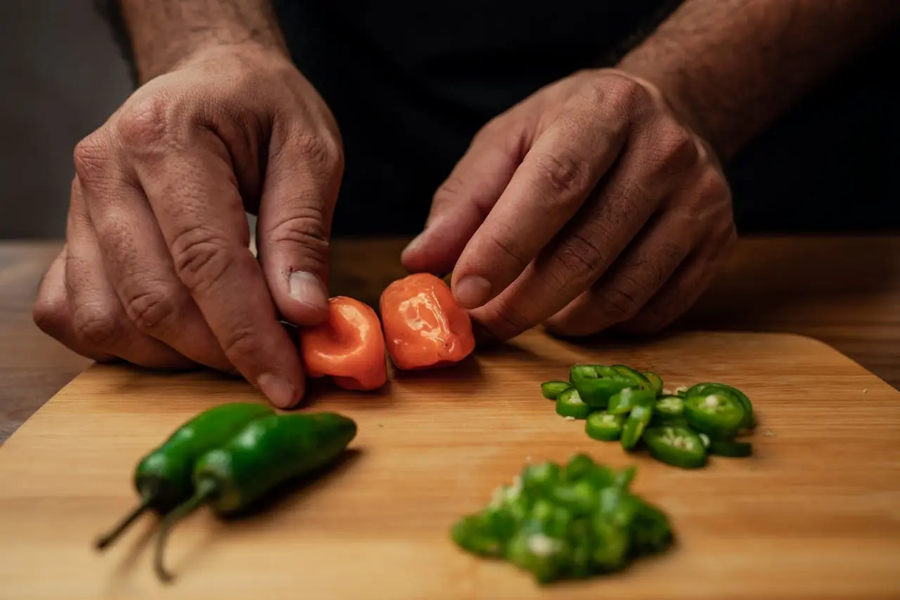two hands holding peppers over a wooden table