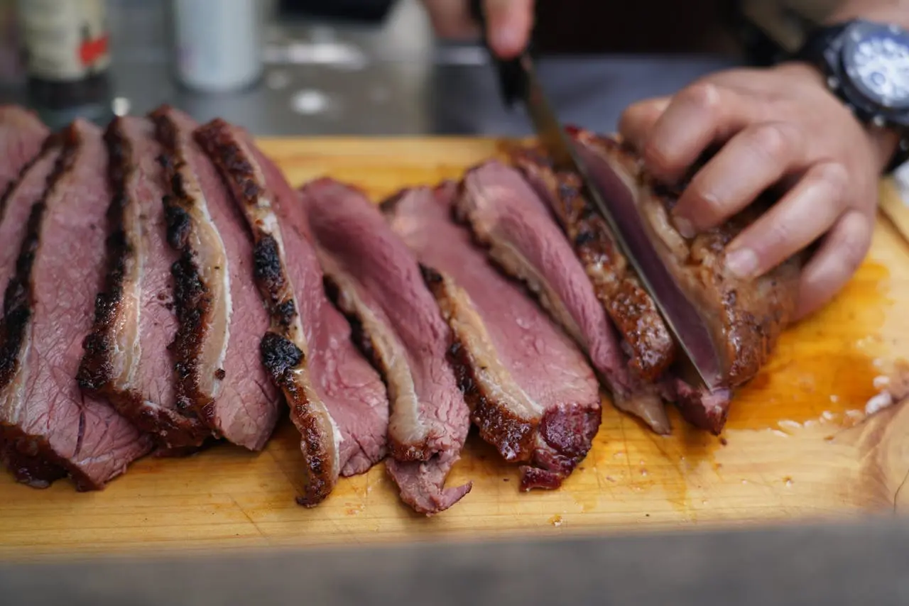 a person cutting a piece of meat in briskets
