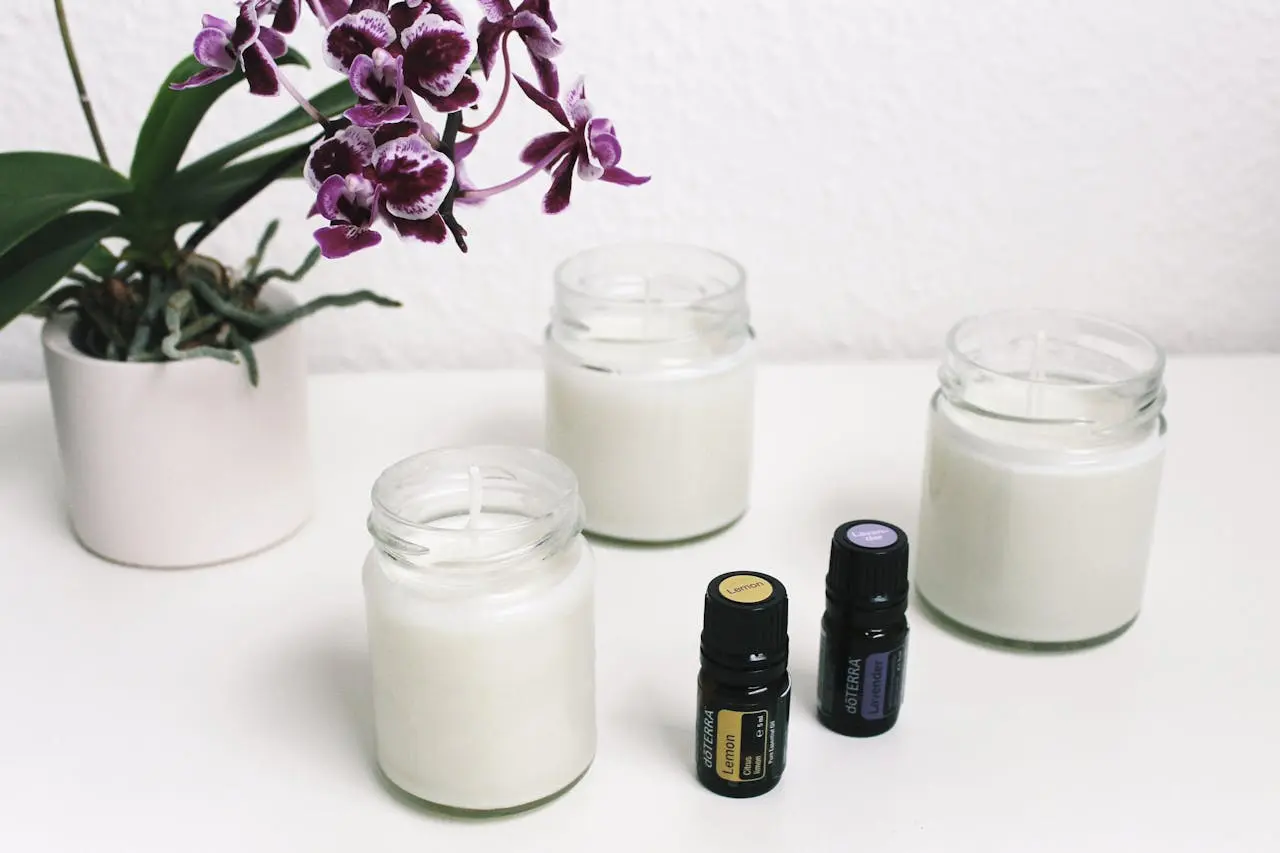 a flower on a jar and three candles with a scented oil next to them
