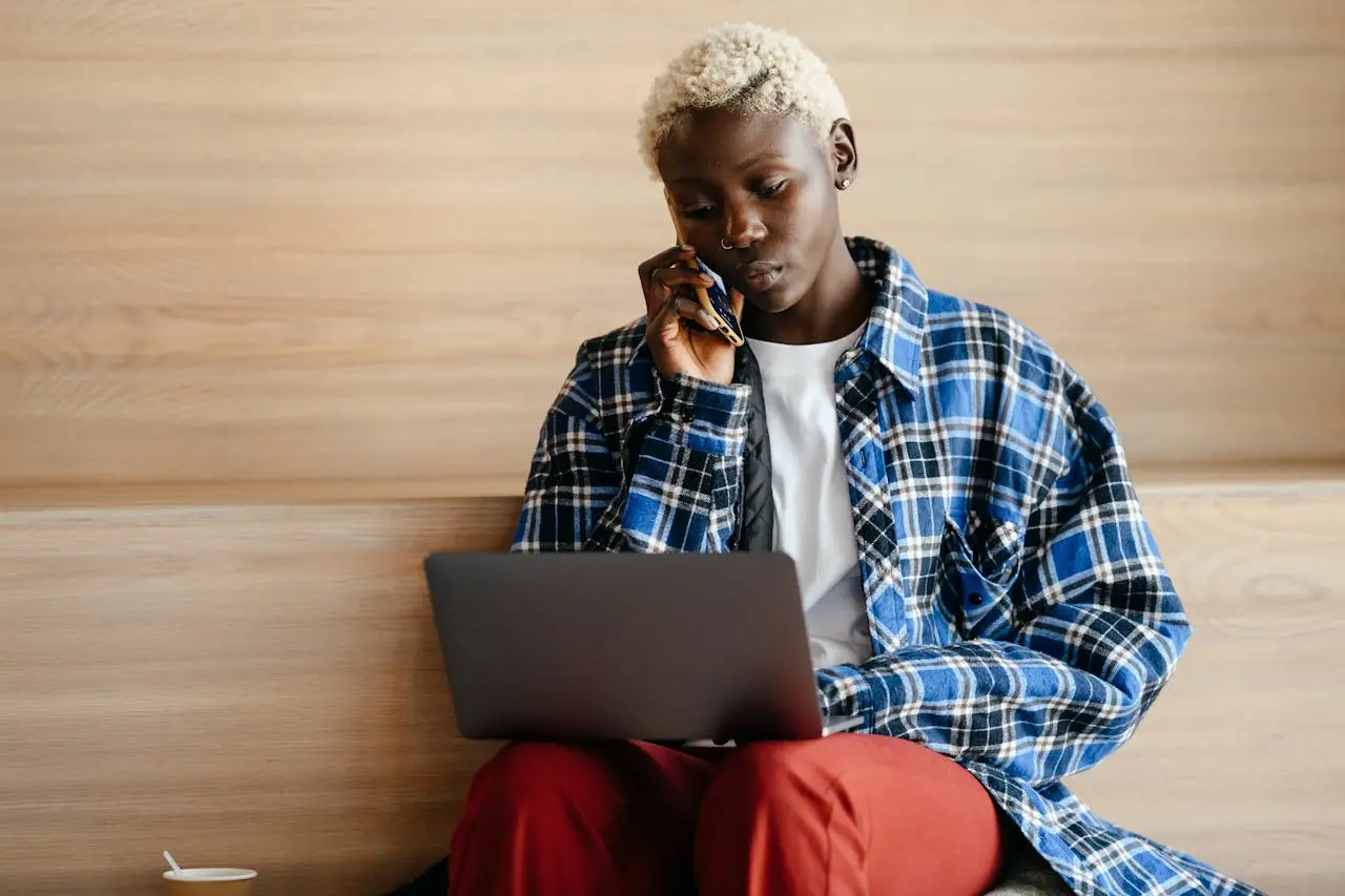 Young woman using a laptop while talking by phone