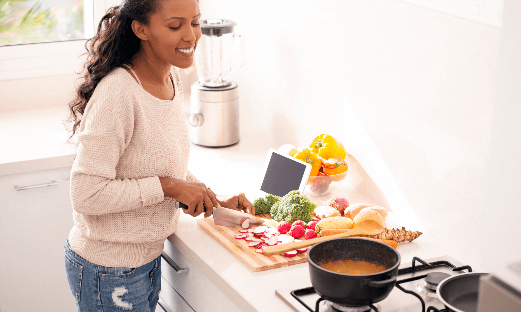 Smiling woman preparing fresh vegetables and cooking in bright kitchen